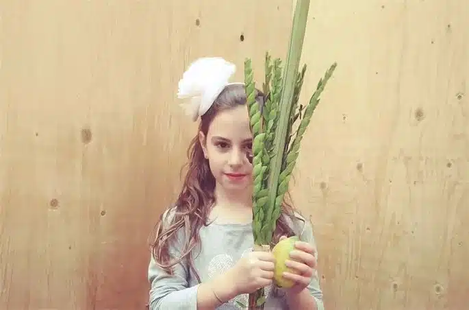 Jewish Girl Holding an etrog (citron), a lulav (palm frond), three hadassim (myrtle twigs) and two aravot (willow twigs) for Jewish Holiday of Sukkot